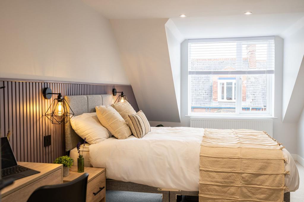 A stylish and well-lit bedroom featuring a comf...