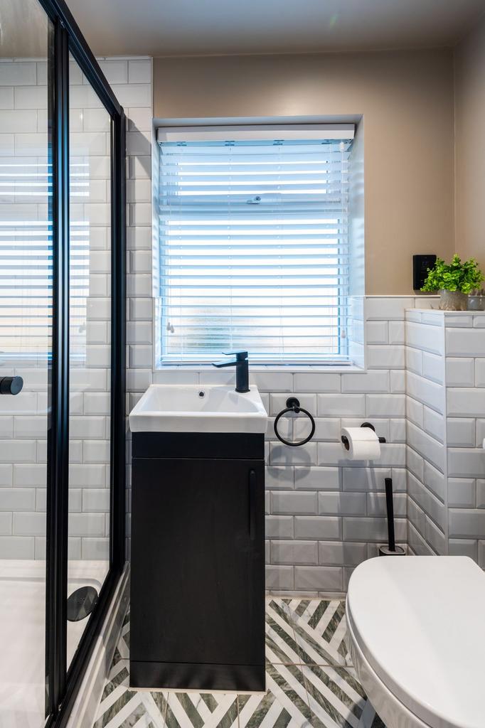 Bright, modern bathroom with a tiled shower, sl...