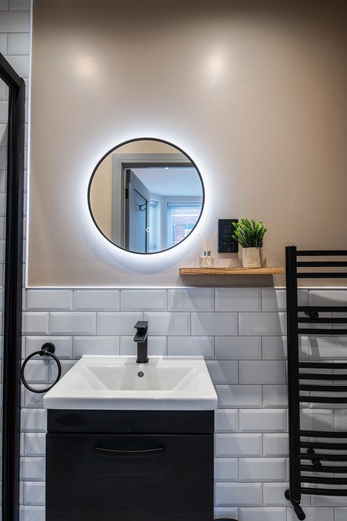 Stylish modern bathroom with a backlit circular...