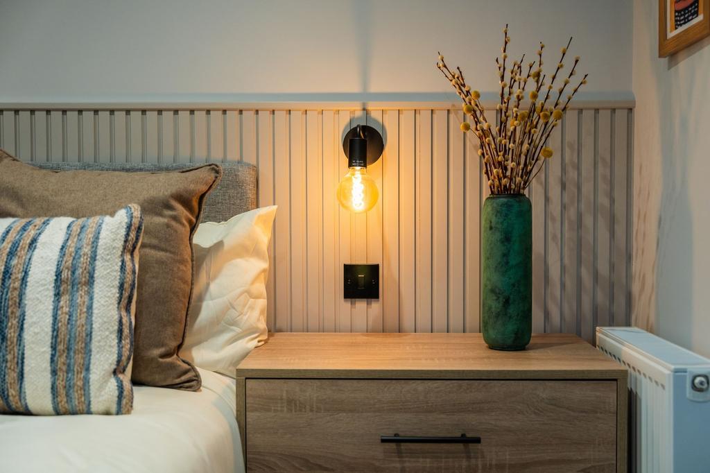 Stylish bedside setup with a warm wall sconce, ...