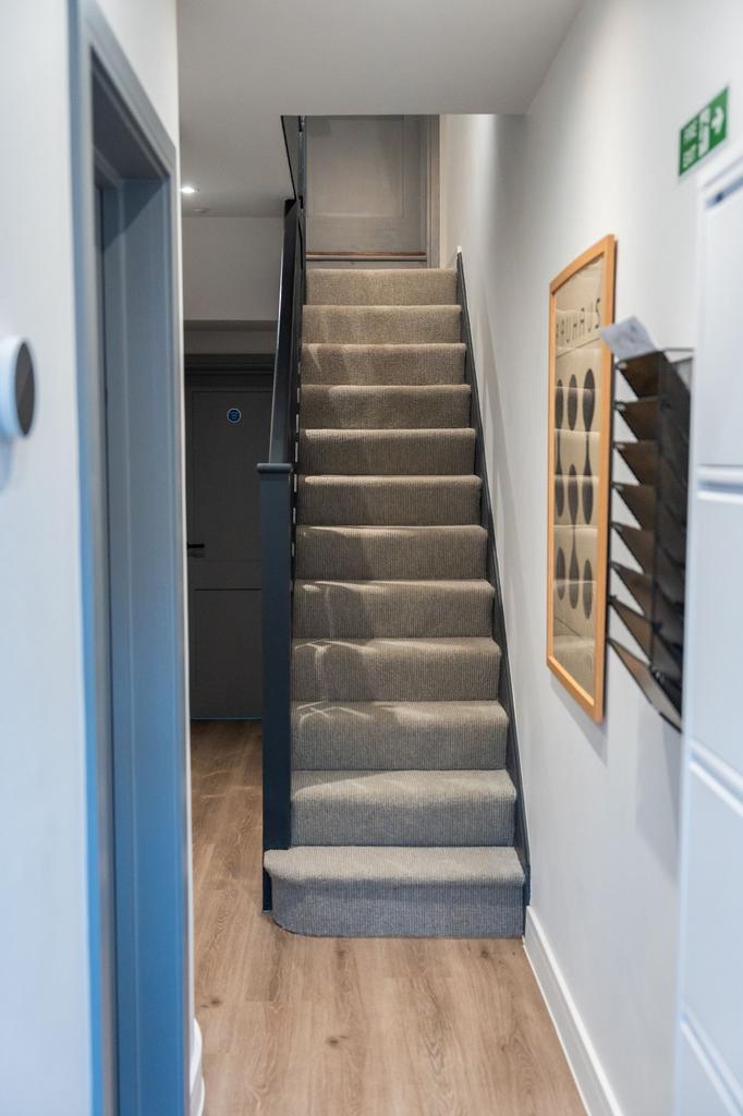 Bright, modern tiled-carpet staircase in a well...
