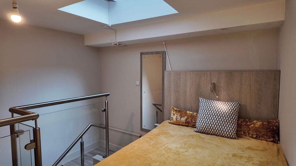 Bright mezzanine bedroom with a skylight, moder...