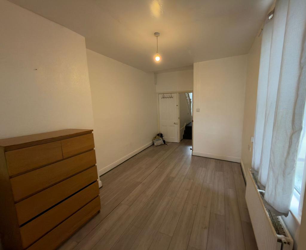 Long, simply furnished bedroom with wood-effect...