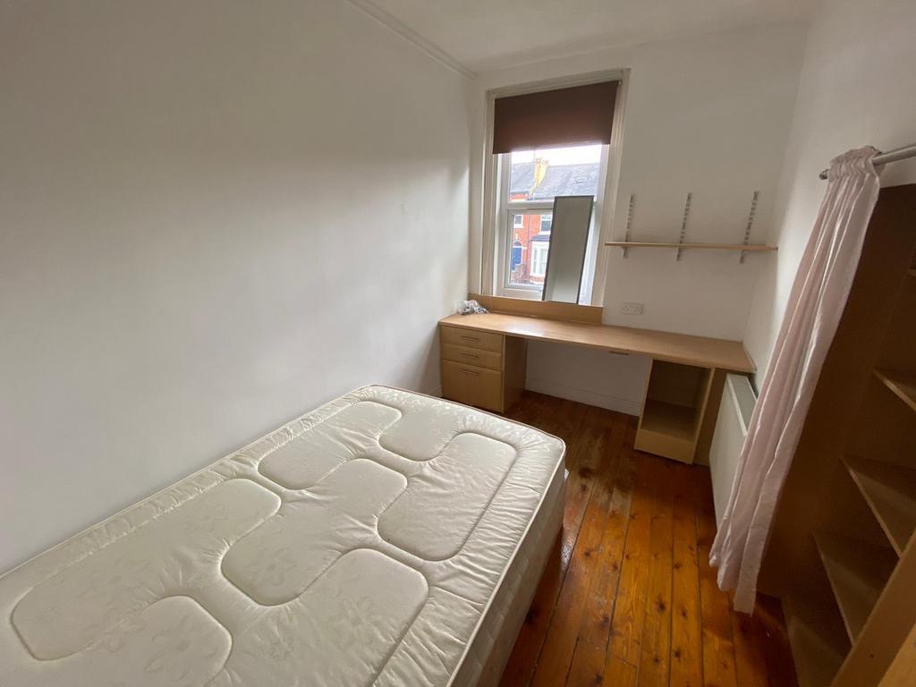 Bright, simply furnished bedroom with wooden fl...