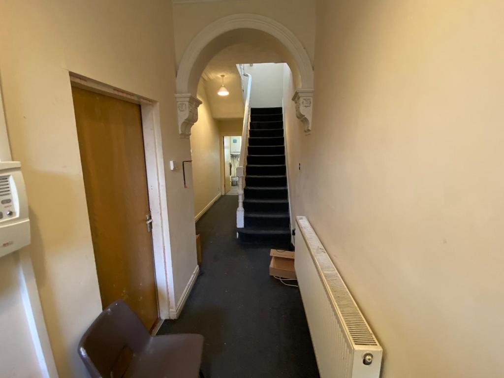 Long entrance hallway with carpeted floor, radi...
