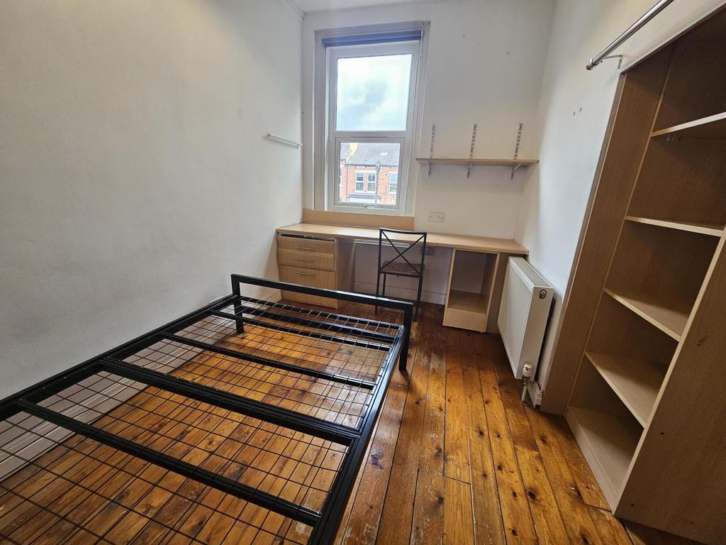 Simple, well-kept bedroom with wooden floors, a...