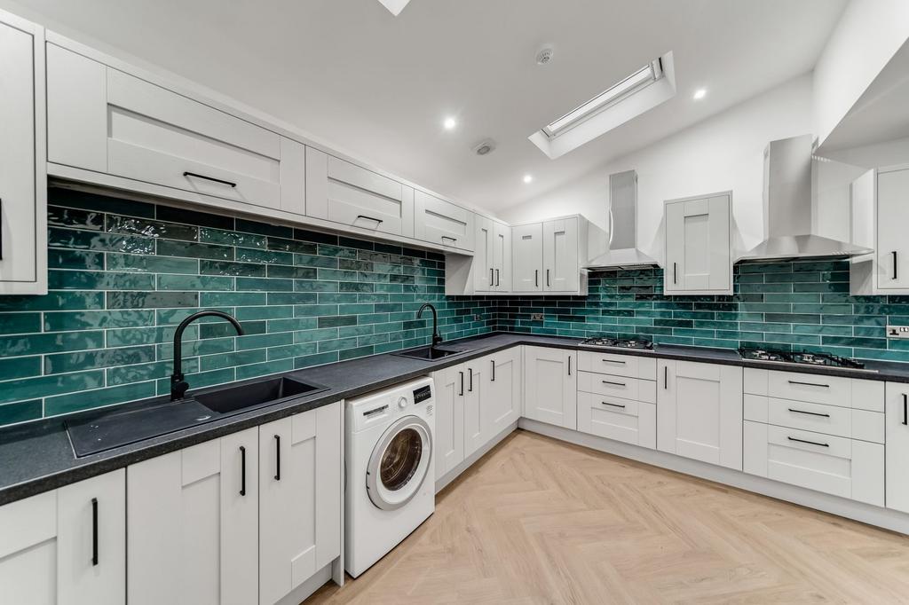 Modern kitchen with white cabinetry, black coun...