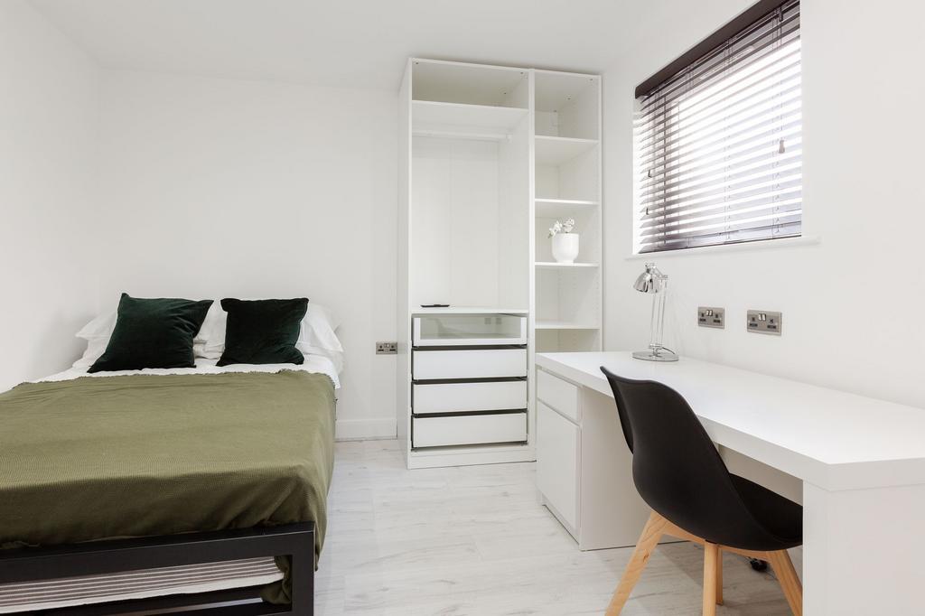 A bright, clean bedroom with a neatly made bed,...