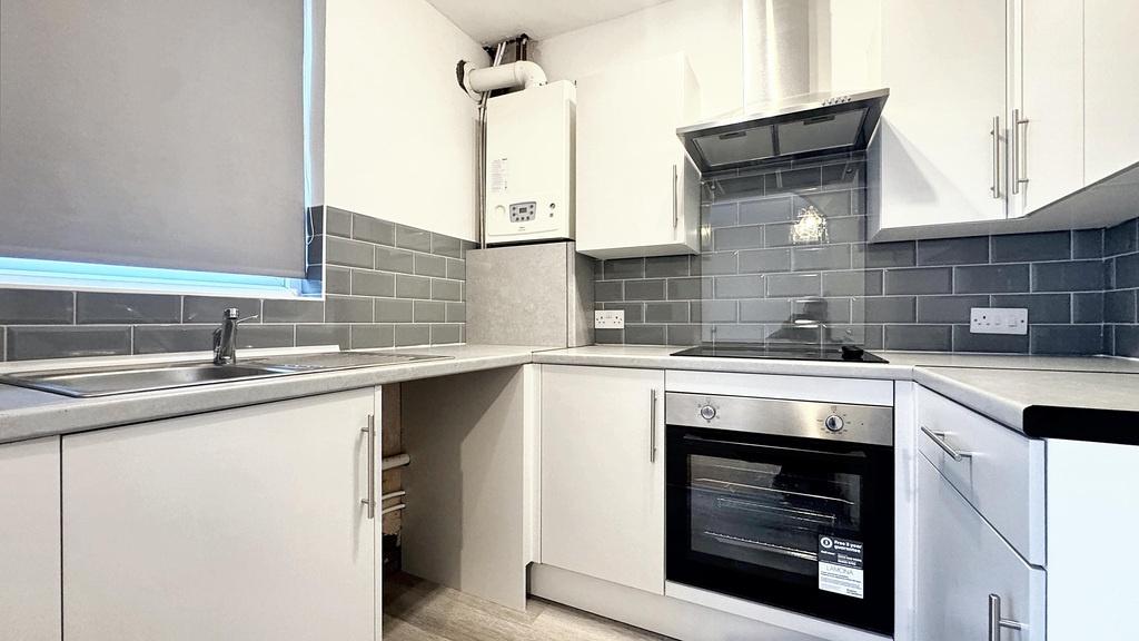 Bright modern kitchen with white cabinetry, gre...