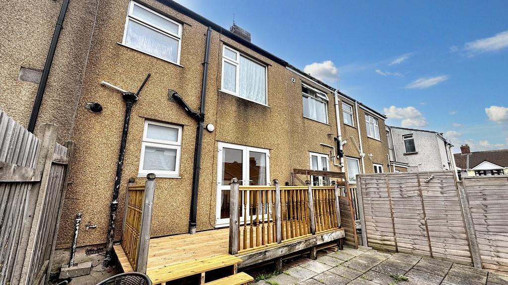 Sunny rear garden with a raised wooden deck and...
