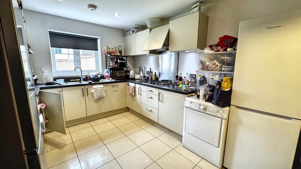 Bright modern kitchen with light cabinetry, til...
