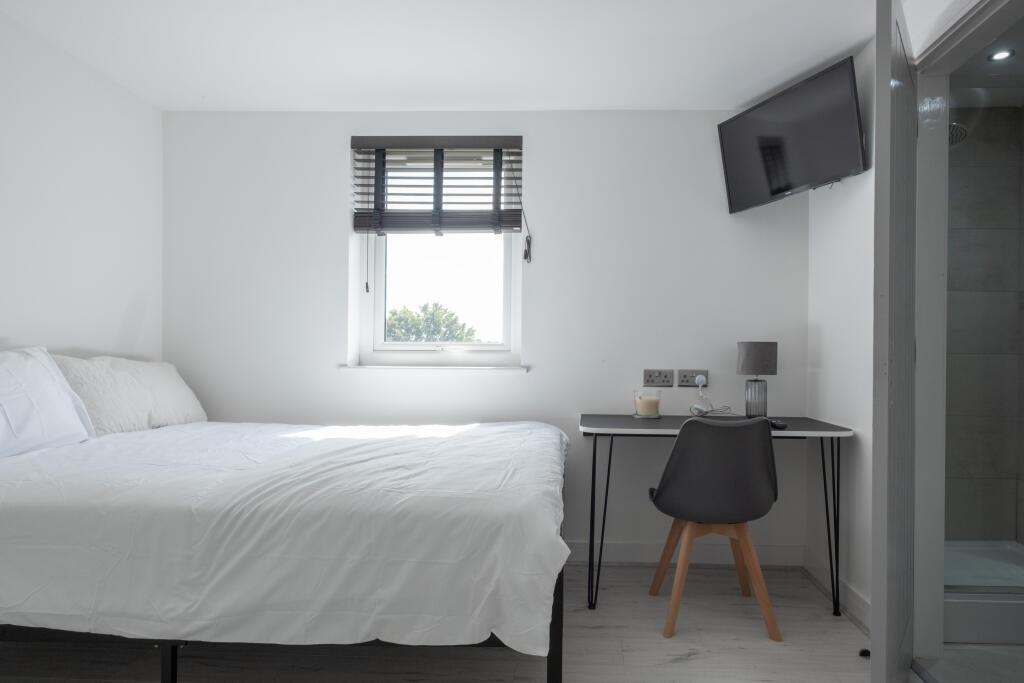 A clean and modern single bedroom featuring a c...