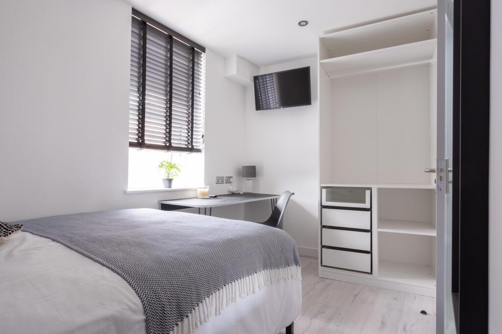 A bright, tidy single bedroom featuring a comfo...