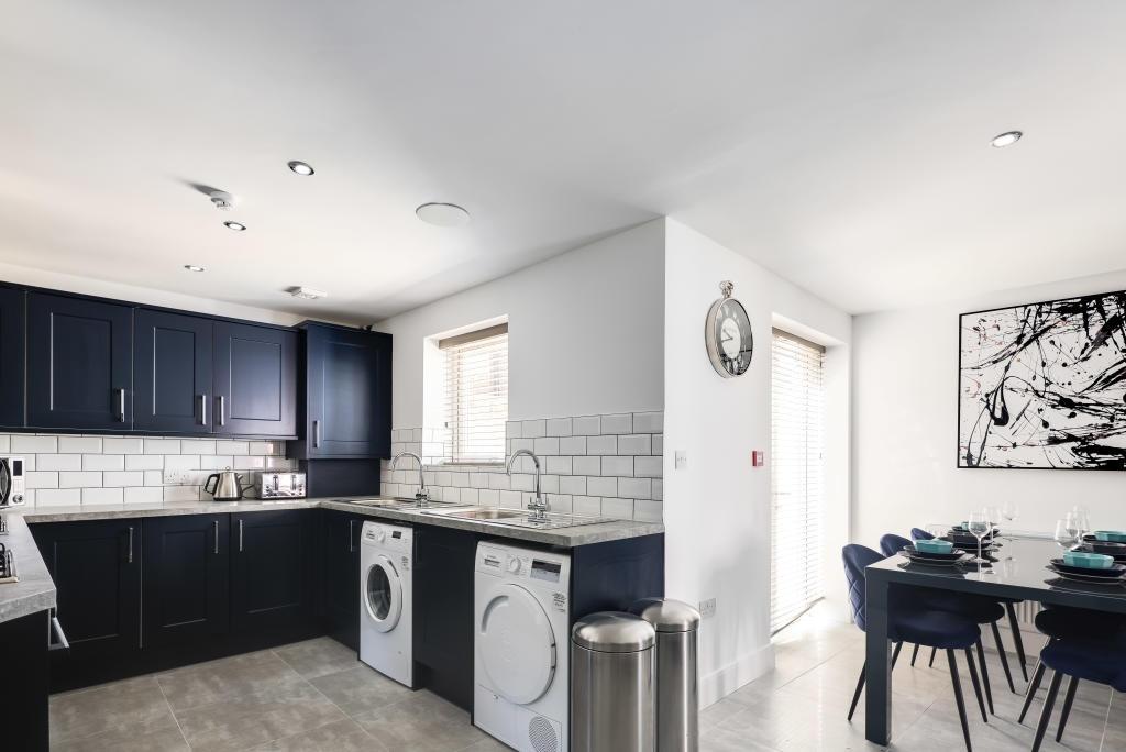 Modern kitchen area featuring dark cabinetry, w...