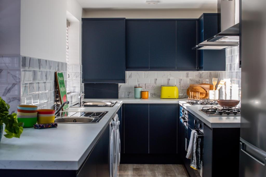 A modern, well-lit kitchen with sleek dark blue...