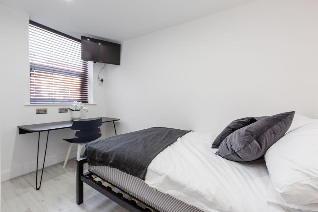 A bright, modern double bedroom featuring a tid...