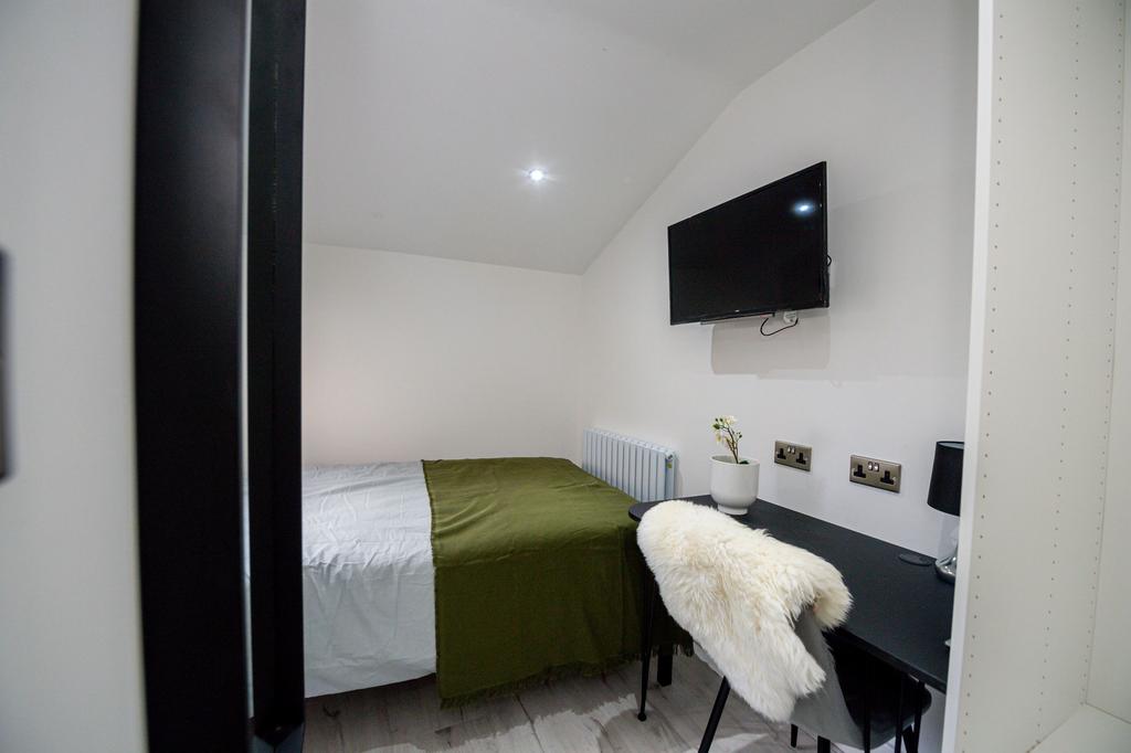 A cozy single bedroom with a neat bed, a desk w...