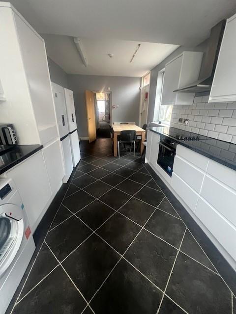 Bright modern galley kitchen with white cabinet...