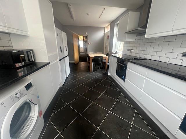 Bright modern galley kitchen with white cabinet...