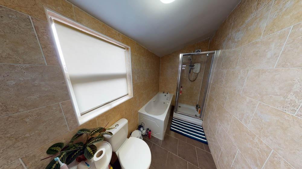 Bright, tiled bathroom with a bath and separate...