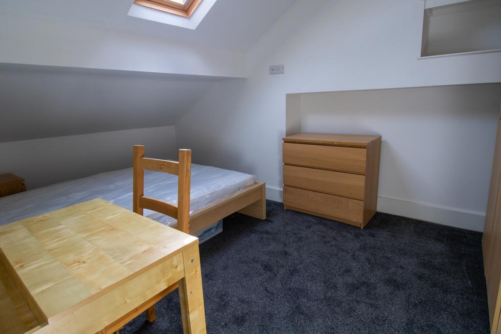 Neat attic single bedroom with a skylight bring...