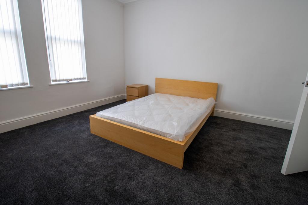 Bright, simply furnished bedroom with a double ...