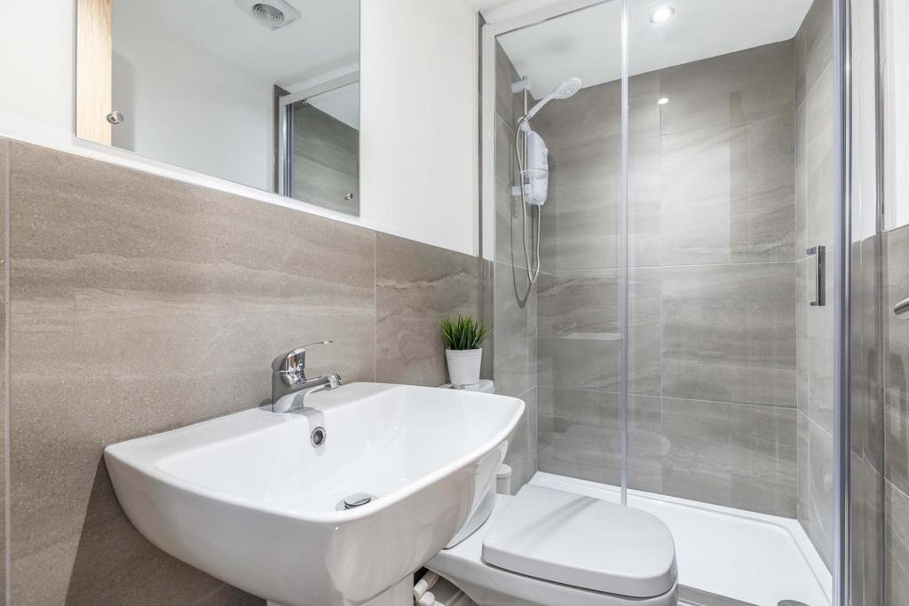 Modern, well-kept bathroom with a walk-in glass...