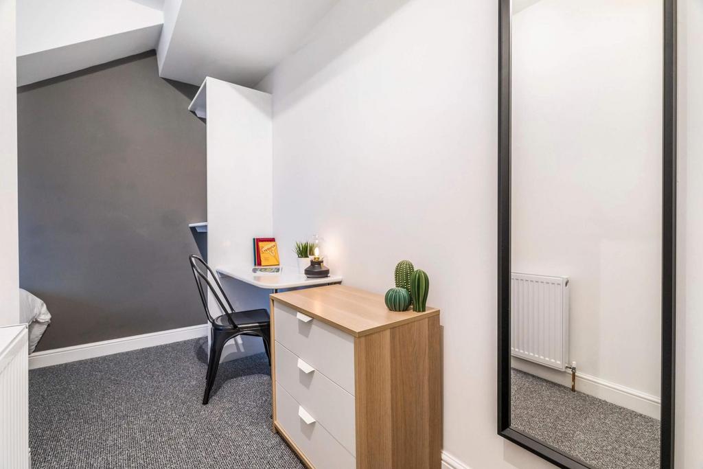 Bright, modern bedroom corner with a small ches...