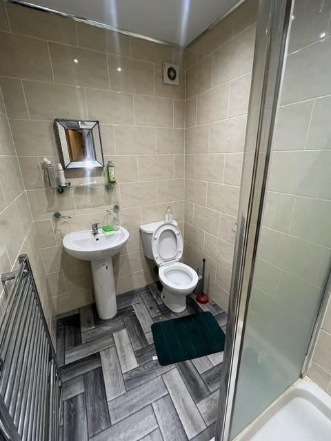 Bright tiled bathroom with a pedestal sink, toi...