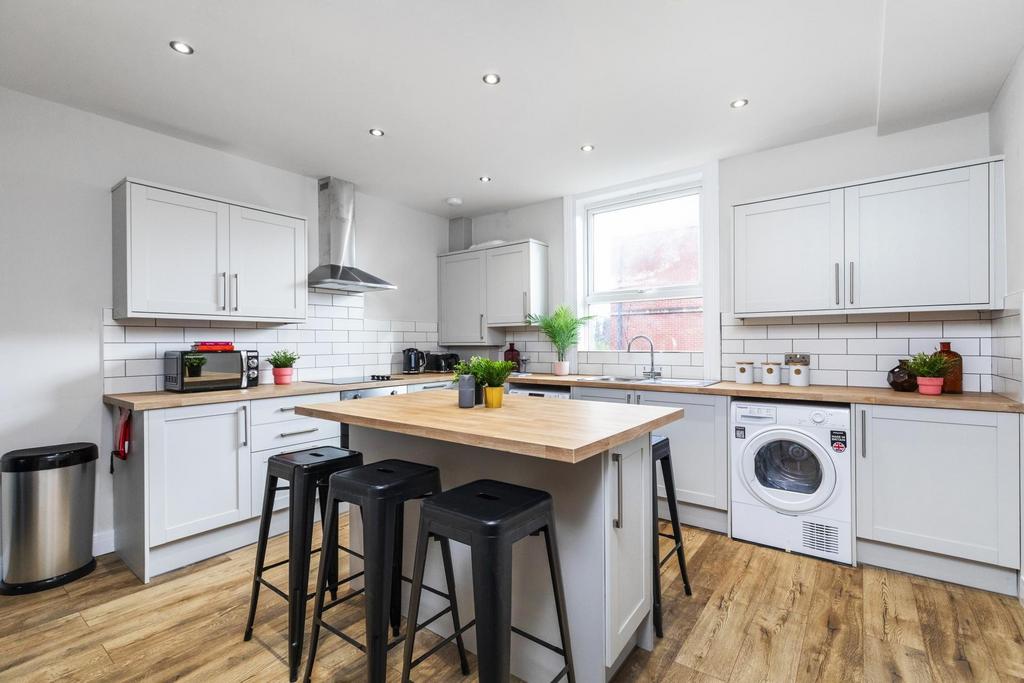 Bright modern kitchen with white cabinetry, a c...