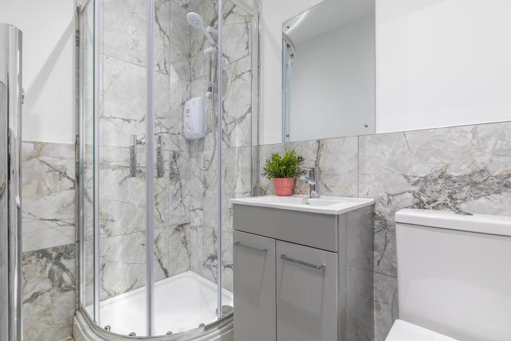 Bright modern bathroom with a corner glass show...