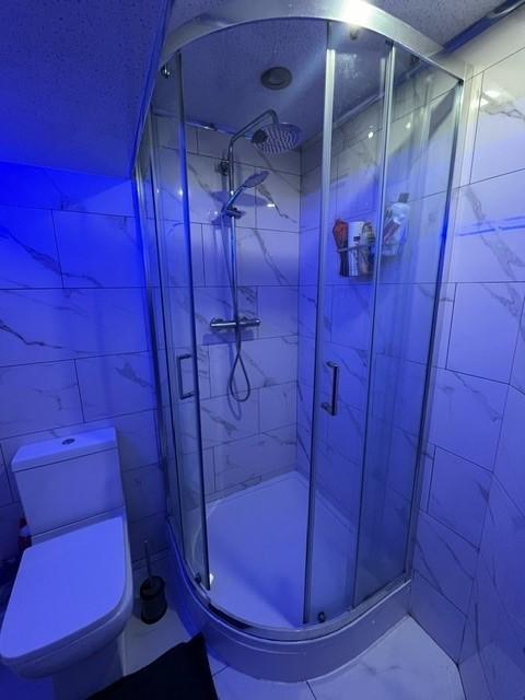 Modern tiled bathroom with a curved glass showe...