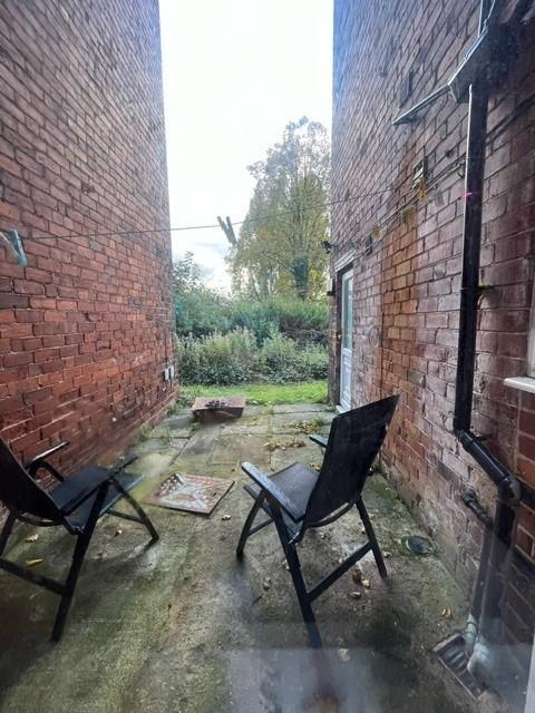Private paved rear yard between brick walls wit...