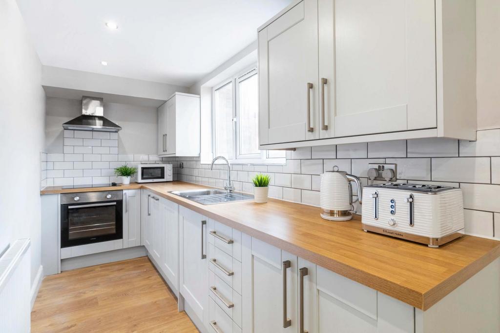 Bright, modern galley kitchen with white cabine...