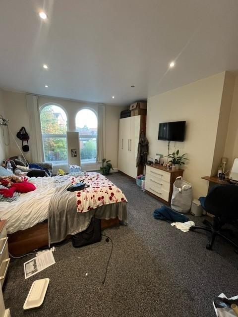 Spacious bedroom with large arched windows lett...