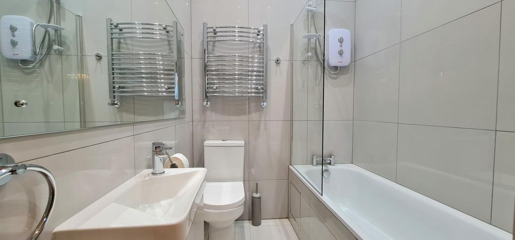 Bright, modern bathroom with a bathtub and sepa...