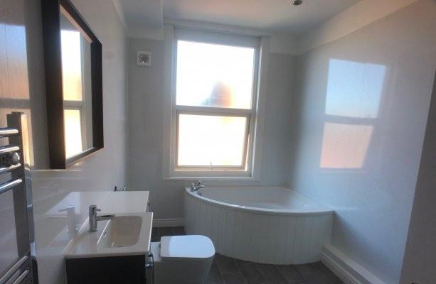 Bright, modern bathroom with a curved corner ba...
