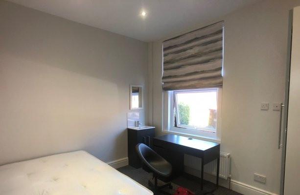Bright, neutrally decorated bedroom with a comf...