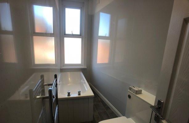 Bright, modern bathroom with a white bathtub, f...