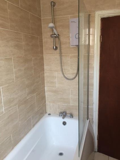 Bright, modern bathroom with tiled walls, a ful...