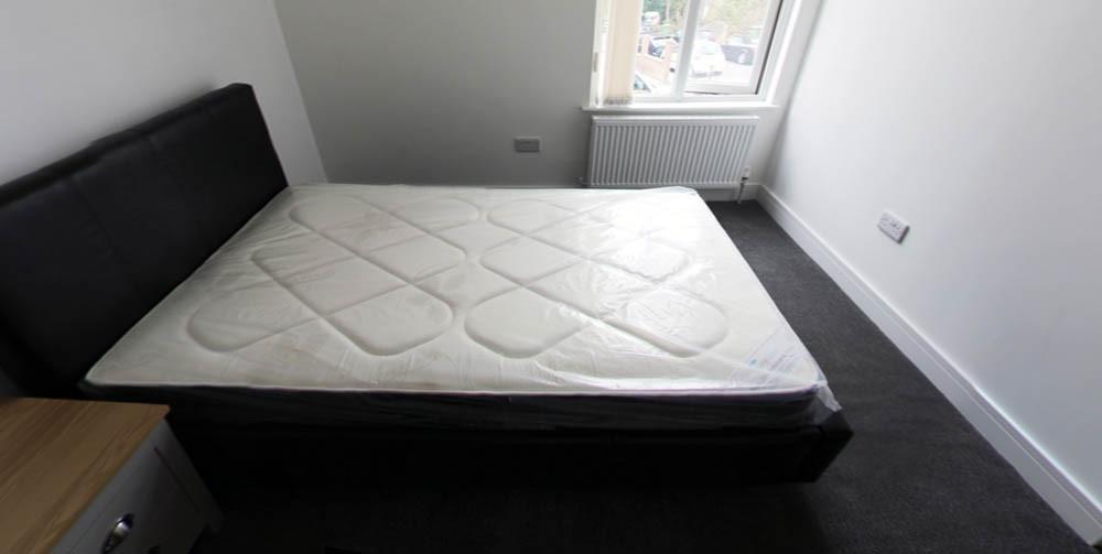 Bright, simply furnished bedroom with a double ...