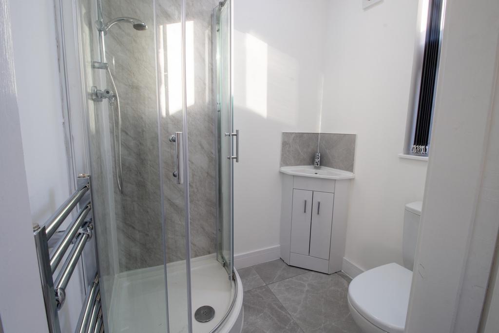 Bright, modern bathroom with a corner glass sho...