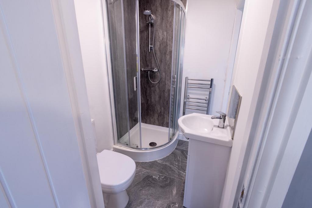 Modern compact bathroom featuring a curved glas...