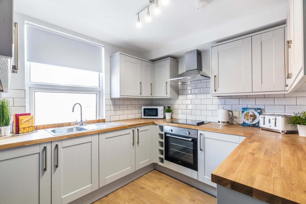 Bright, modern kitchen with light cabinetry, wo...