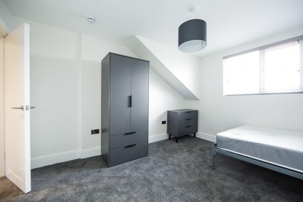 Bright, neutrally decorated bedroom with a sing...