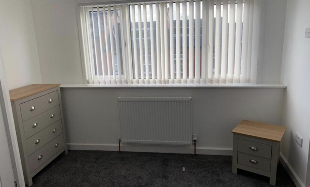 Bright, simply furnished bedroom with a large w...