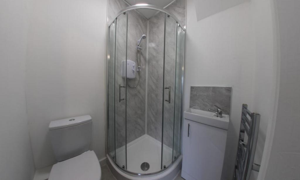 Modern compact bathroom with a corner glass sho...
