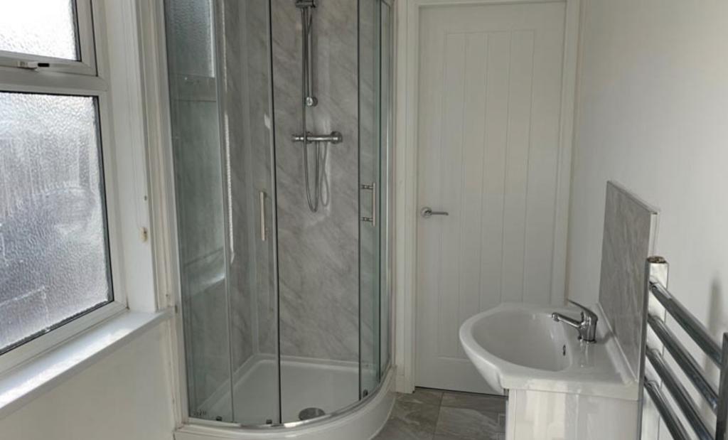 Bright, modern bathroom with a corner glass sho...
