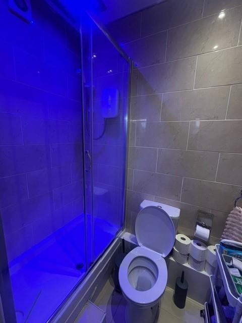 Contemporary tiled bathroom featuring a glass-e...