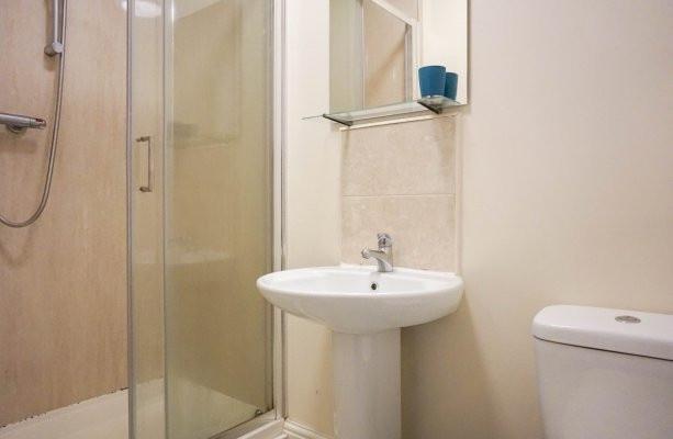 Bright, neutrally finished bathroom with a glas...